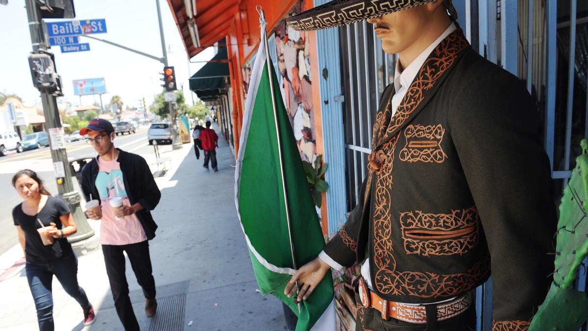 Pedestrians pass by a mannequin dressed in a charro outfit in Boyle Heights.