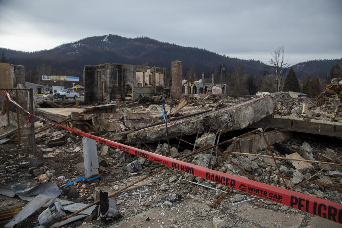 The ruins of buildings marked off with red tape and mountains in the background 