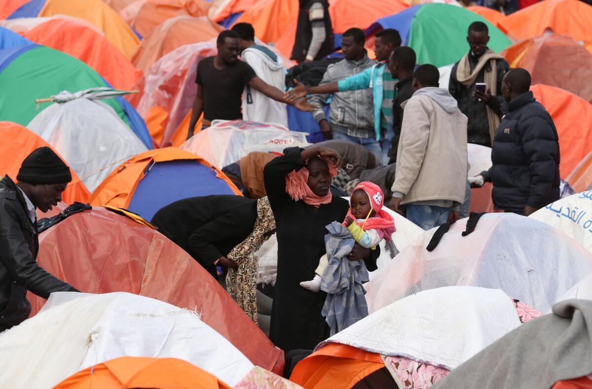 A Sudanese woman holds her child in front of a tent pitched outside the United Nations refugee agency in Amman, Jordan, in December.