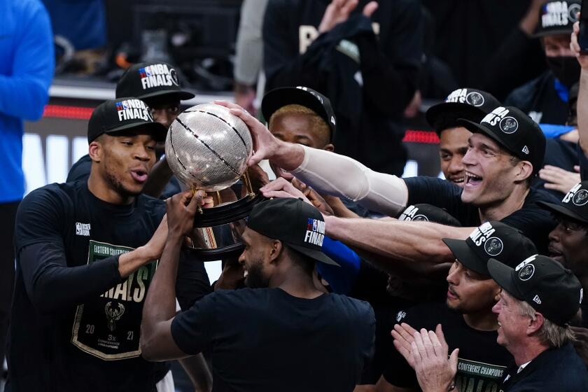 Bucks players hoist the Eastern Conference title trophy after defeating the Hawks in Game 6 on July 3, 2021, in Atlanta.