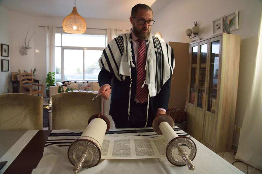 FILE - In this Aug. 16, 2020 file photo, Alex Peterfreund, a co-founder of Dubai's Jewish community and its cantor, prepares to read from the Torah in Dubai, United Arab Emirates. Half a year after the United Arab Emirates and Bahrain established diplomatic relations with Israel, Gulf Jewish communities are emerging from the shadows and raising their public profiles. (AP Photo/Jon Gambrell, File)