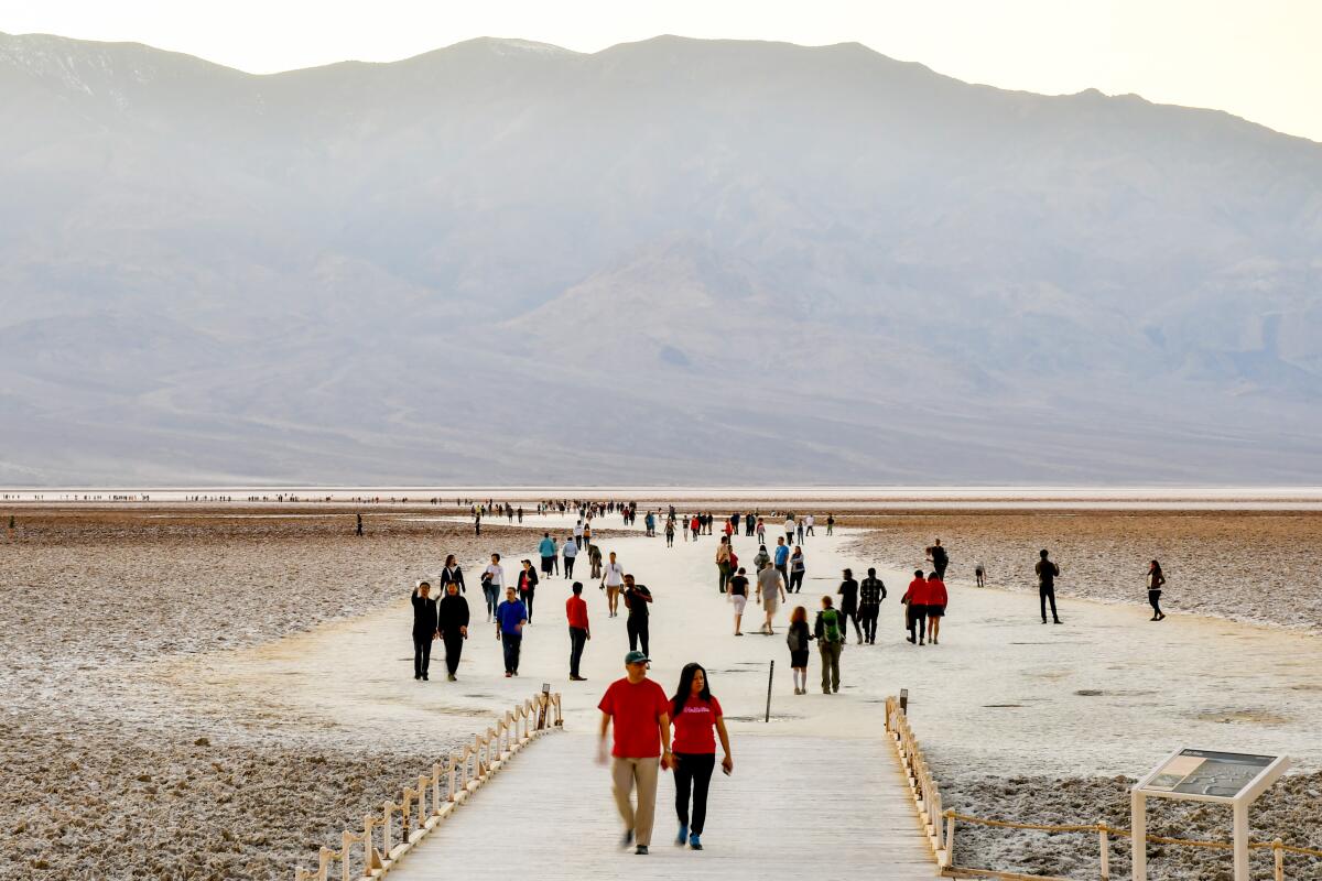 People walk on a wide, sandy path at Badwater, Death Valley National Park.