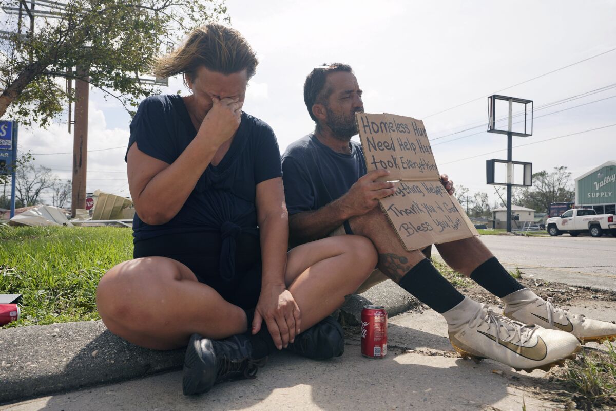 RETRANSMISSION TO CORRECT SPELLING OF SURNAME TO HEBERT - Homeless couple Angelique Hebert, and husband Wilfred Hebert, ask for help on a sidewalk as they try to recover from the effects of Hurricane Ida Tuesday, Aug. 31, 2021, in Houma, La. (AP Photo/Steve Helber)