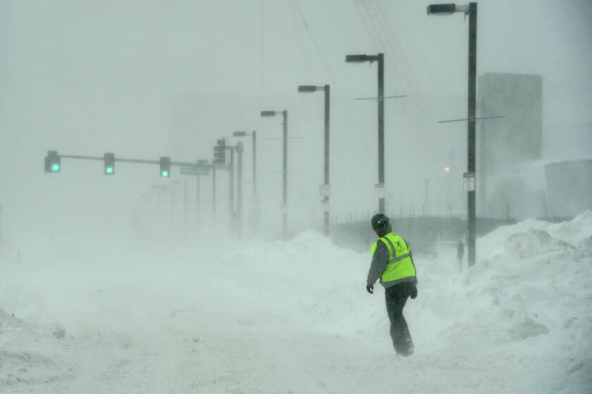 A construction worker walks in the blowing snow along Seaport Boulevard in Boston on Monday.