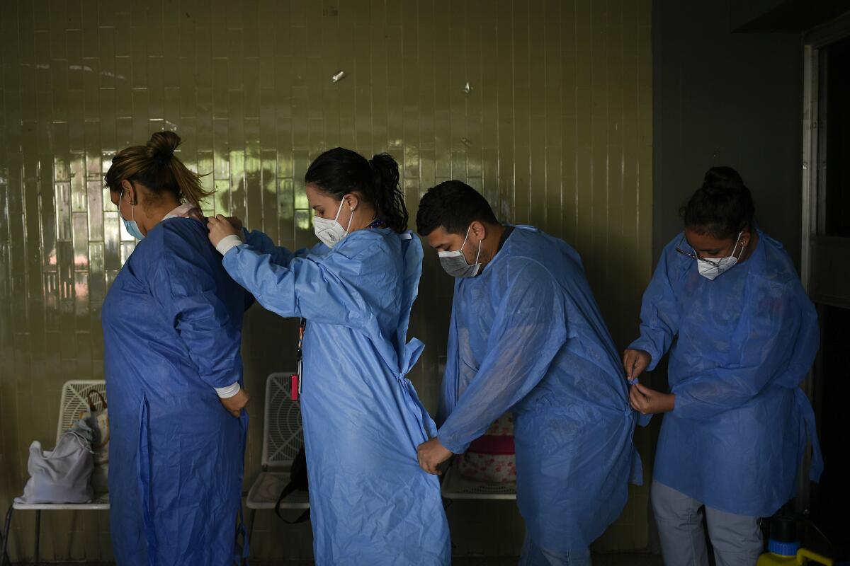 Los médicos del gobierno se ponen batas protectoras mientras se preparan para realizar pruebas