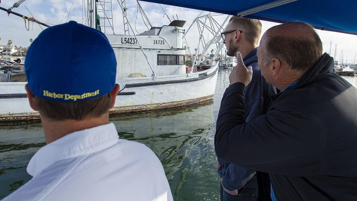 Tommy Tupman, left, with Newport Beach harbor services, shows Zack and Brent Beasley an old 35-foot fishing boat called Espousa that the city put up for auction Tuesday. No one bid on it or two other large vessels in the auction.