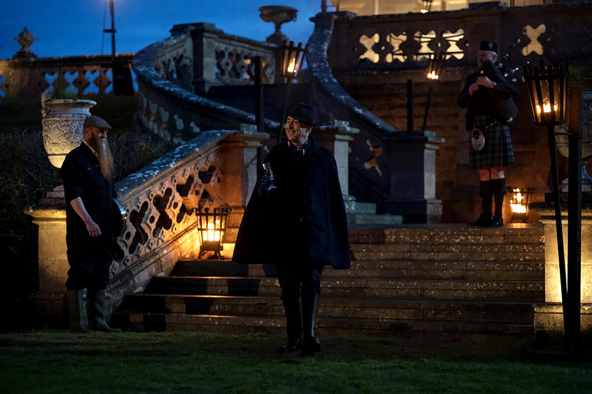 Alan Cumming wears a cape as he walks down the stairs of a Scottish castle on "The Traitors."