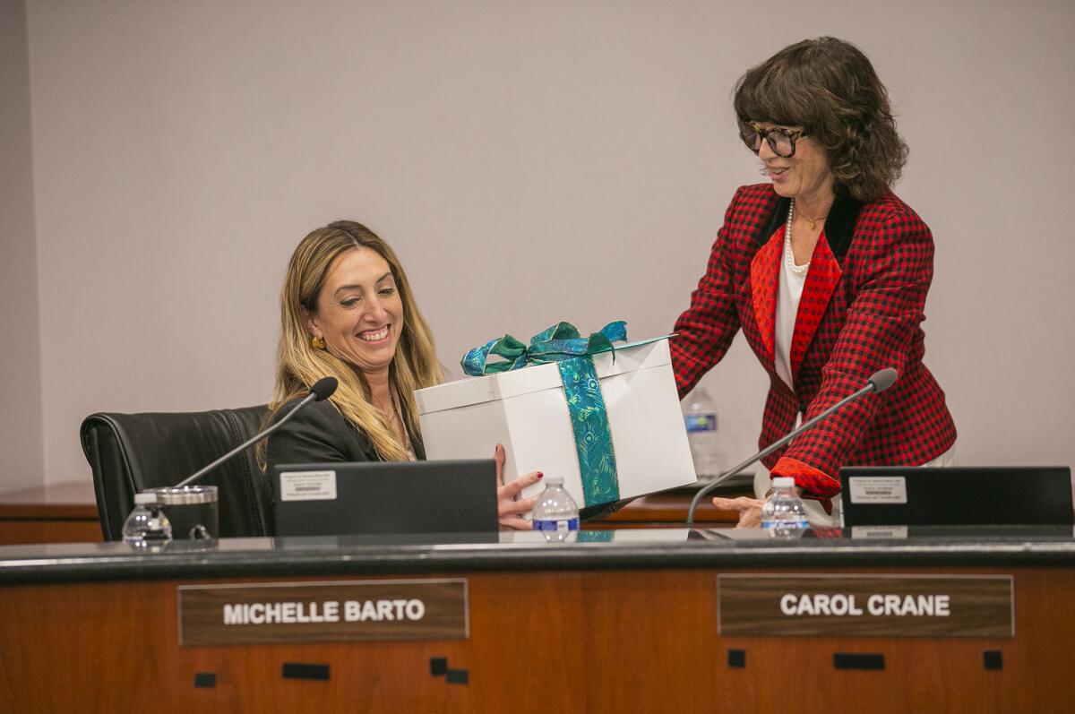New Board Vice President Carol Crane, right, hands outgoing President Michelle Barto a gift in a meeting Tuesday.
