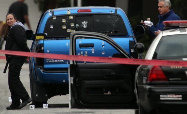 Police investigators work around a blue pickup truck riddled with bullets in the 19500 block of Redbeam Avenue in Torrance after a police protection team fired on it. The officers were protecting the neighborhood in the wake of threats against an officer, allegedly by former LAPD Officer Christopher Jordan Dorner.
