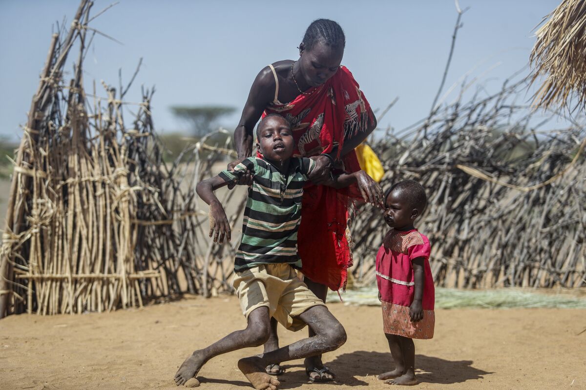 FILE - A mother helps her malnourished son stand after he collapsed near their hut in the village of Lomoputh in northern Kenya, Thursday, May 12, 2022. Politicians and experts met in Madrid on Friday, June 17, 2022, to discuss ways to tackle drought and the increasing spread of deserts across the globe. (AP Photo/Brian Inganga, File)
