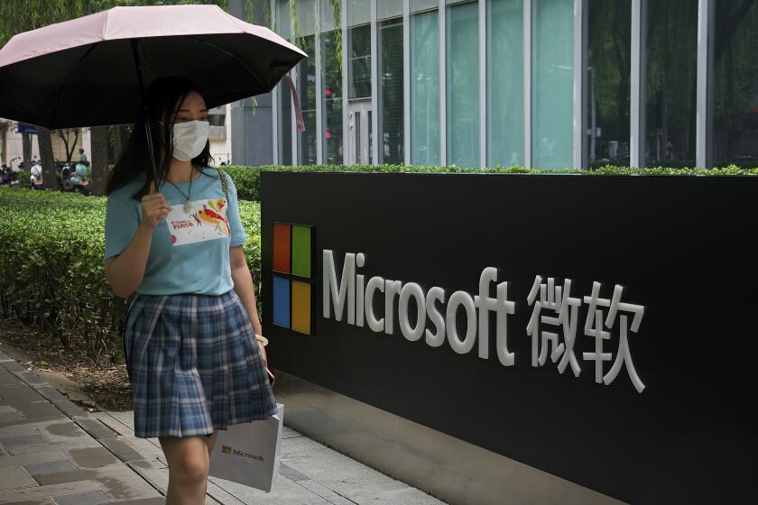 A woman wearing a face mask to help curb the spread of the coronavirus walks by the Microsoft office building in Beijing, Tuesday, July 20, 2021. The Biden administration and Western allies formally blamed China on Monday for a massive hack of Microsoft Exchange email server software and asserted that criminal hackers associated with the Chinese government have carried out ransomware and other illicit cyber operations. (AP Photo/Andy Wong)
