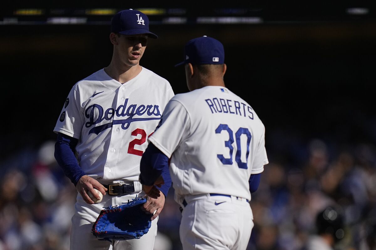 Dodgers manager Dave Roberts speaks to pitcher Walker Buehler.
