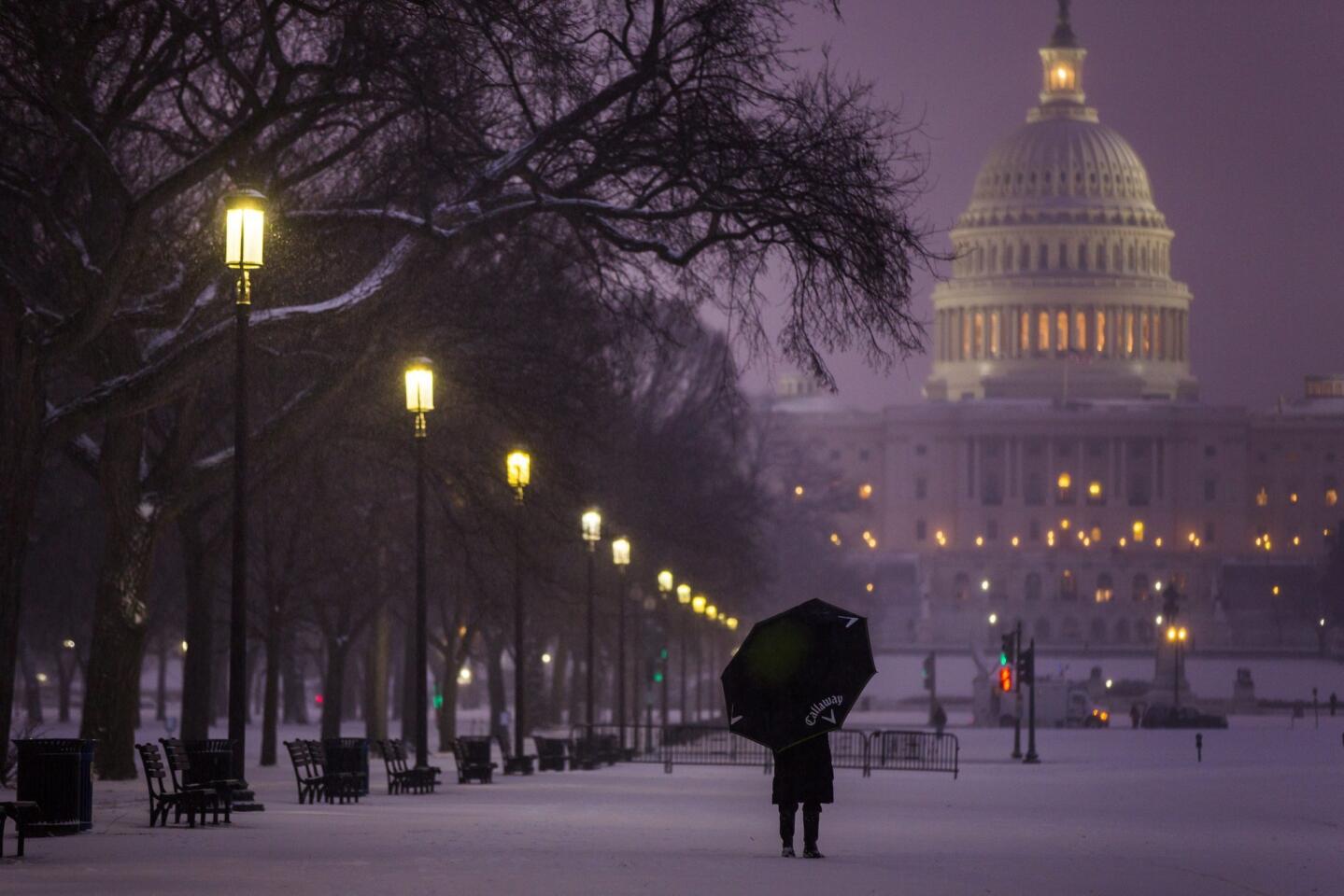 A visitor to the National Mall pauses in a late afternoon snowfall in Washington, D.C.
