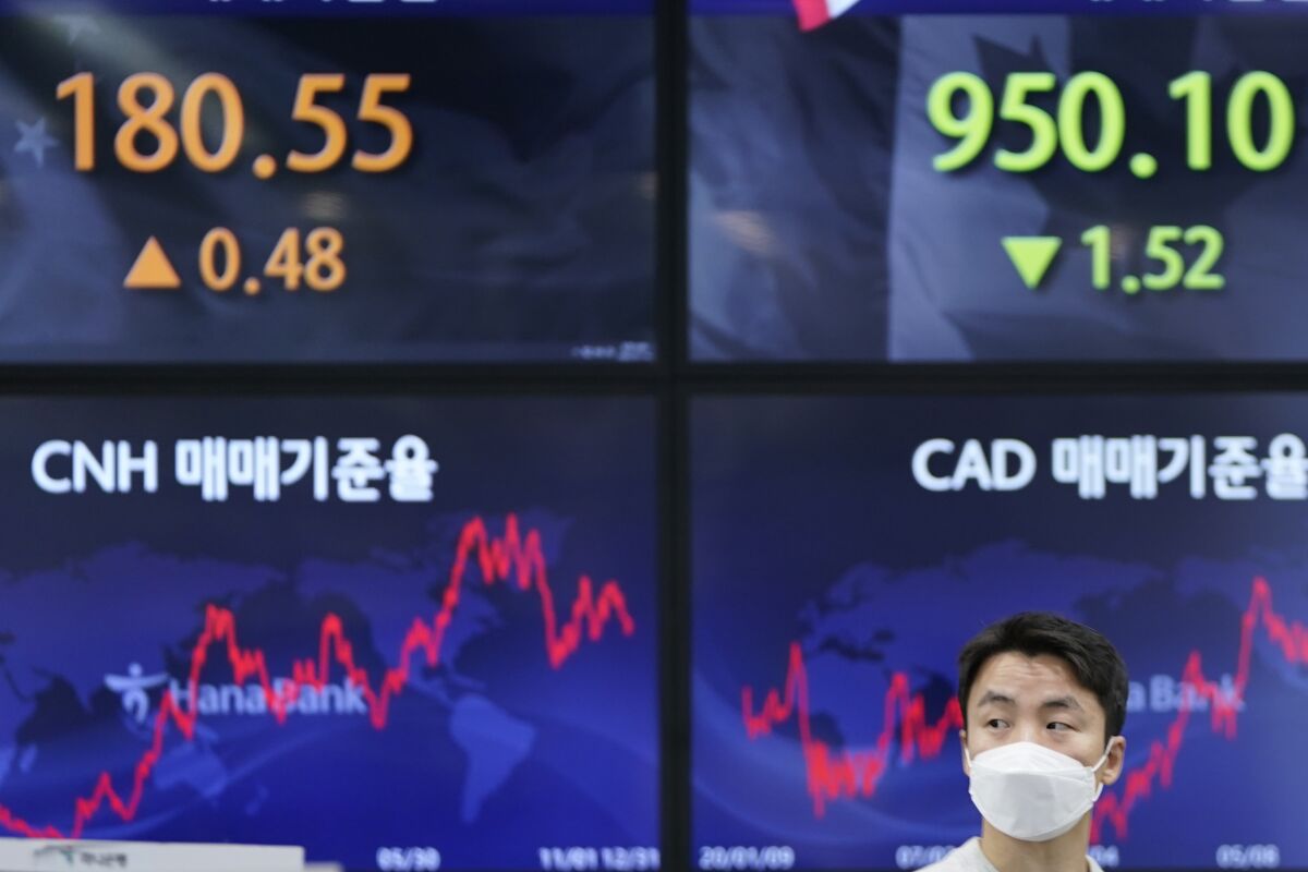 A currency trader walks near the screens showing the foreign exchange rates at a foreign exchange dealing room in Seoul, South Korea, Friday, Jan. 14, 2022. Asian shares slipped Friday after a retreat on Wall Street that left the Nasdaq composite down 2.5%.(AP Photo/Lee Jin-man)