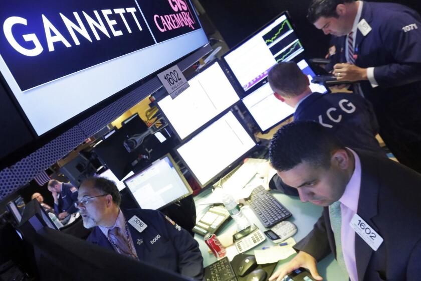 FILE - In this Aug. 5, 2014, file photo, specialist Michael Cacace, foreground right, works at the post that handles Gannett, on the floor of the New York Stock Exchange. Shareholders of USA Today owner Gannett have rebuffed an attempt to overthrow its board. Gannett, which also owns dozens of other newspapers, says its slate of eight directors had beaten opposing candidates nominated by a media group vying to revive its previously rejected takeover bid for Gannett. (AP Photo/Richard Drew, File)