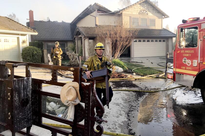 WHITTIER CA FEBRUARY 10, 2021 - Los Angeles County firefighters carry valuables out of a home burned in the Sycamore fire near Whittier Thursday afternoon. (Gina Ferazzi / Los Angeles Times)