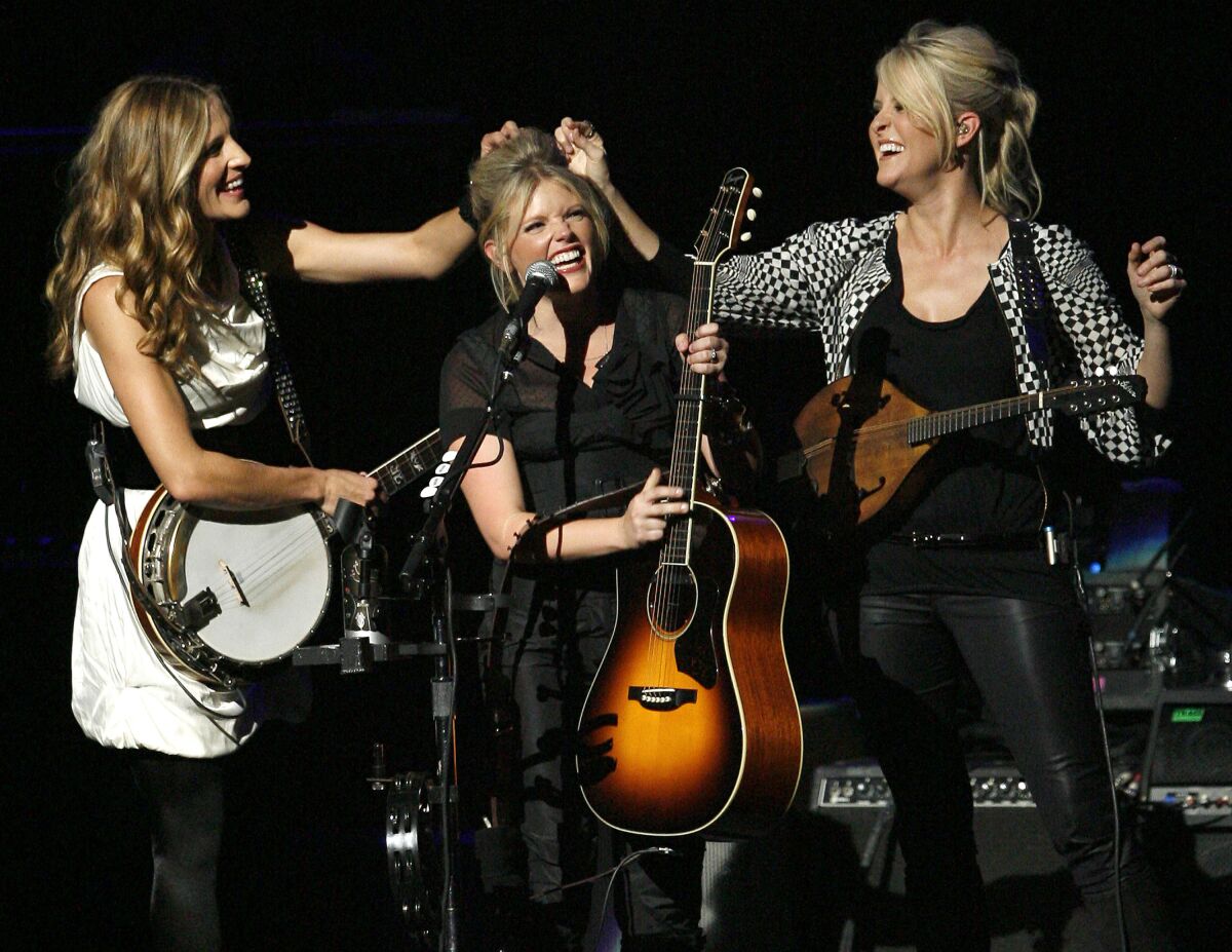 FILE - In this Oct. 18, 2007 file photo, Emily Robison, left, and Martie Maguire, right, adjust Natalie Maines' hair as the Dixie Chicks perform at the new Nokia Theatre in Los Angeles. The Grammy-winning country group, who recently changed their name to The Chicks, have a new album "Gaslighter" out July 17, 2020. (AP Photo/Gus Ruelas, File)