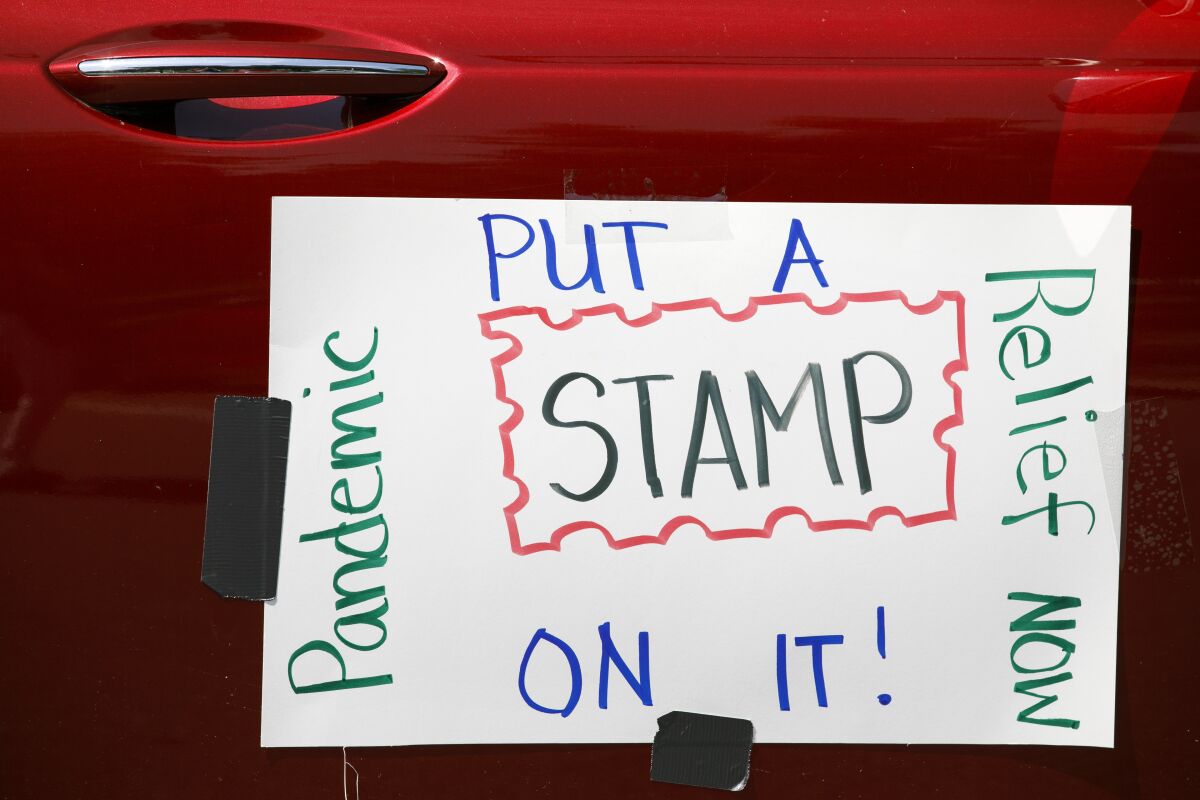 A car displays a sign asking Congress to approve emergency funding for the Postal Service