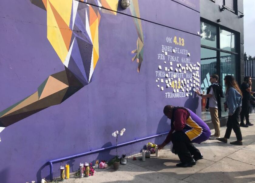 A man in a Lakers jersey pays tribute to Kobe Bryant at the Shoe Palace mural in Los Angeles.