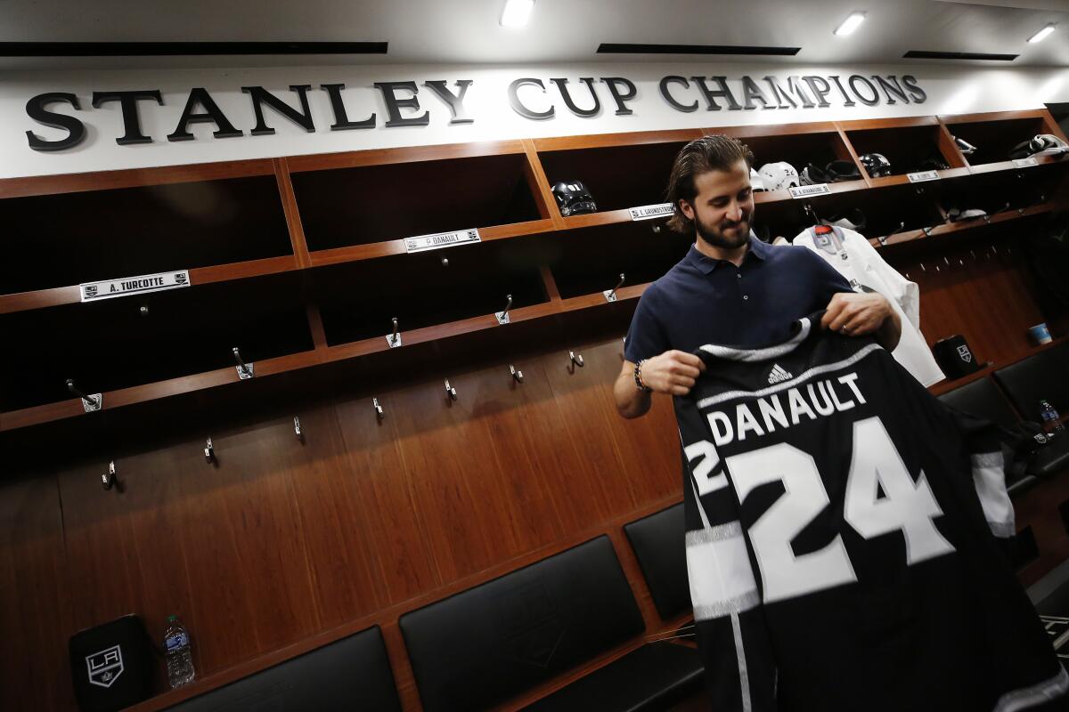 Kings player Phillip Danault tries his team jersey for the first time in the locker room.