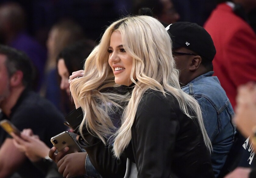 A side view of a blond Khloé Kardashian sitting at a Lakers game