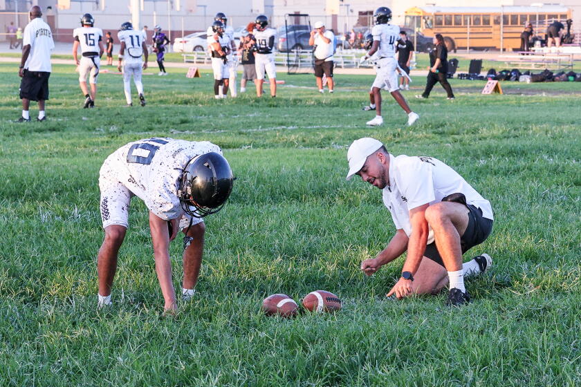 Bell's field wasn't mowed this week, so San Pedro assistant Andres Srsen pulls some grass to help kicker Dylan Moreno.