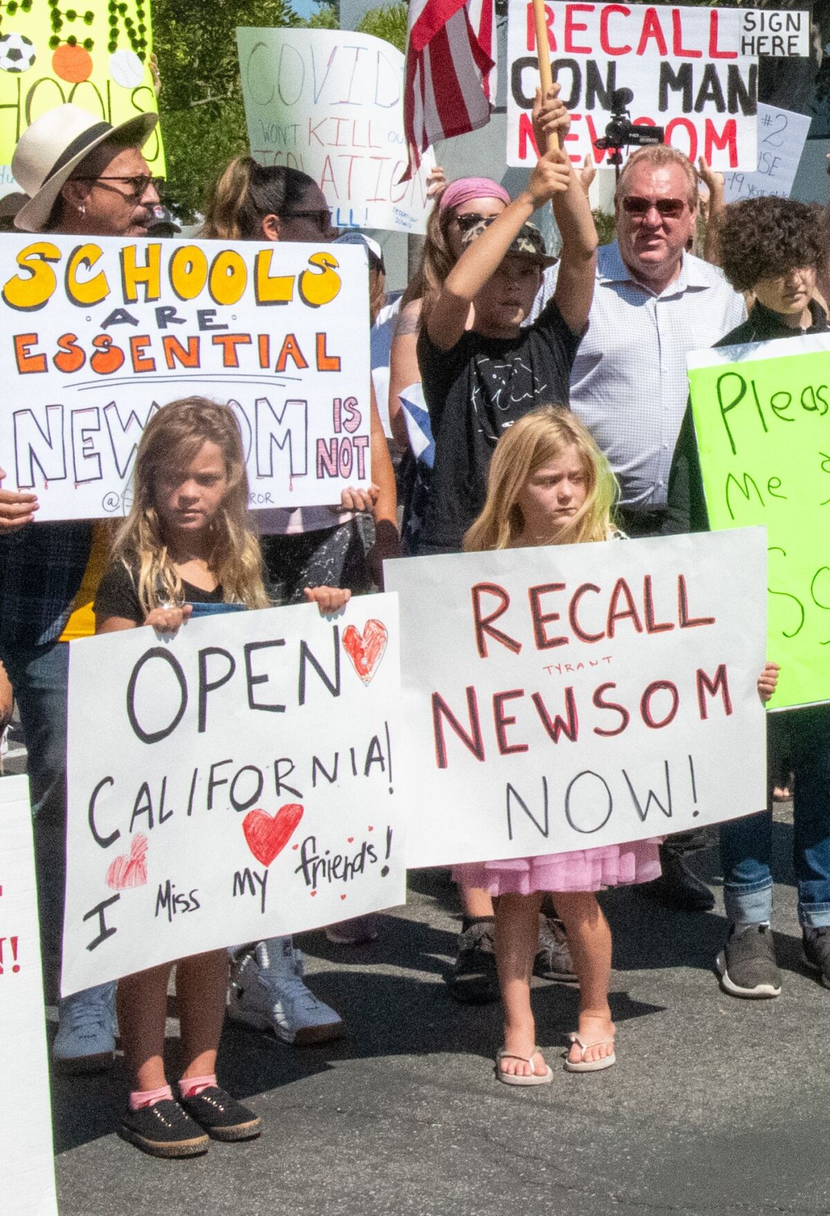 Children hold signs reading "Open California: I Miss my friends" and calling for the recall of Gov. Gavin Newsom.