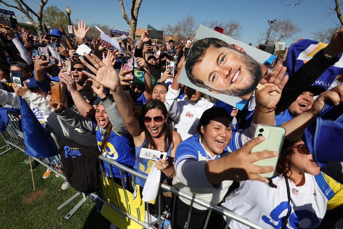 Enthusiastic Rams fans cheer as players roll along Exposition Park Drive to celebrate their Super Bowl LVI win
