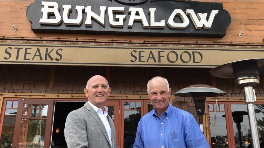 Steve Rosansky, left, president and chief executive of the Newport Beach Chamber of Commerce, greets Jim Walker, owner of the Bungalow restaurant in Corona del Mar, who has been named the chamber's Business Person of the Year.