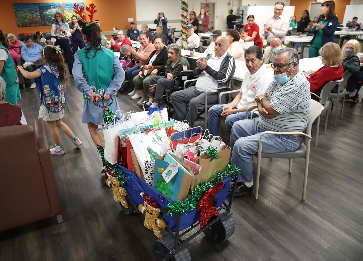 Girl Scouts haul in a wagon of gift bags at Santa Ana Adult Day Health Care Center.