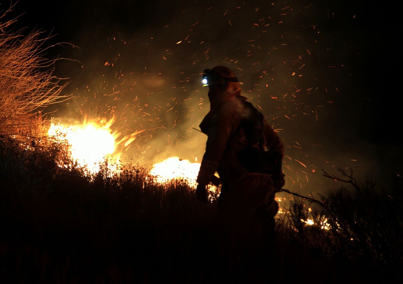 A firefighter keeps a close eye on swirling embers while battling the Silver fire. The fire had destroyed at least 12 structures Wednesday night.