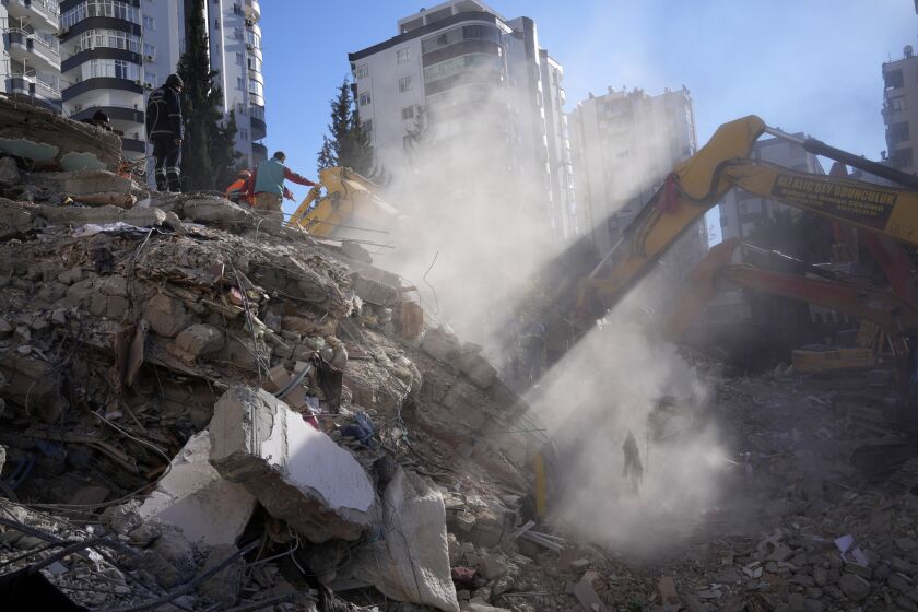 Emergency teams search for people in the rubble of a destroyed building in Adana, southern Turkey, Tuesday, Feb. 7, 2023. A powerful earthquake hit southeast Turkey and Syria early Monday, toppling hundreds of buildings and killing and injuring thousands of people. (AP Photo/Hussein Malla)