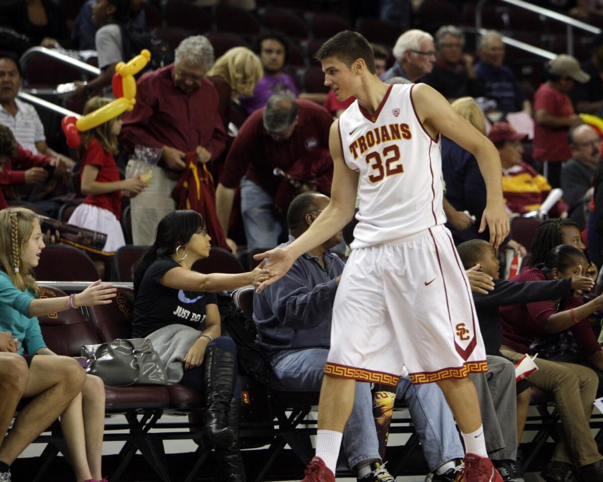 USC forward Nikola Jovanovic high-fives a fan courtside after a team scrimmage at the Galen Center on Oct. 27, 2013.