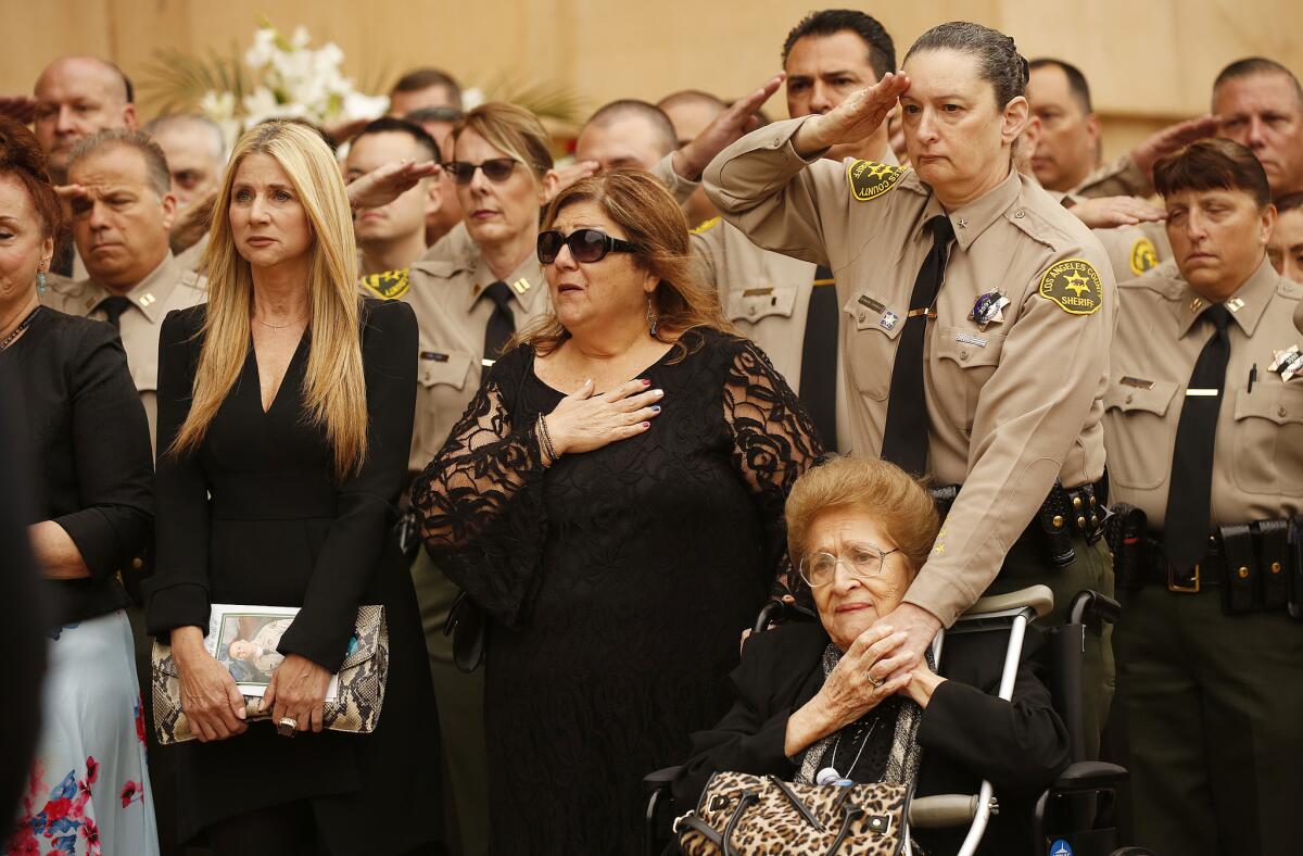 Deputy Joseph Solano's godmother, Sallome Yanez, right, other relatives and Los Angeles County sheriff's deputies salute his casket during a memorial service for the 13-year veteran of the Sheriff's Department.