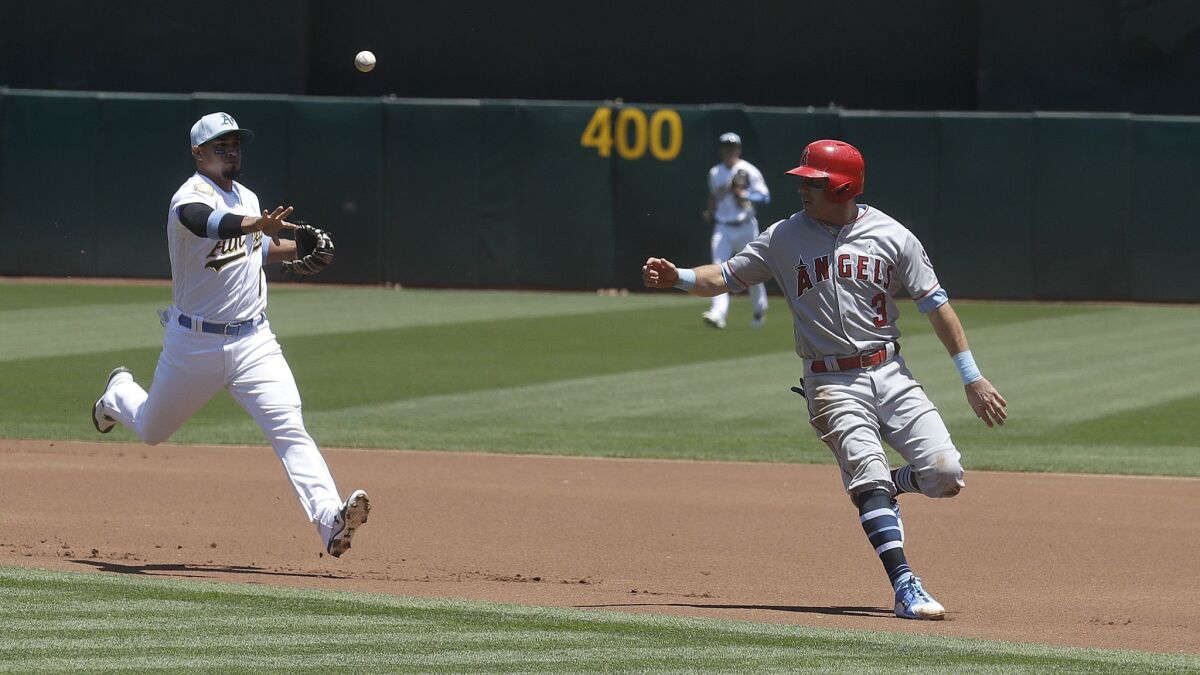 Oakland second baseman Franklin Barreto, left, throws to first base as the Angels' Ian Kinsler is caught in a rundown during the first inning.