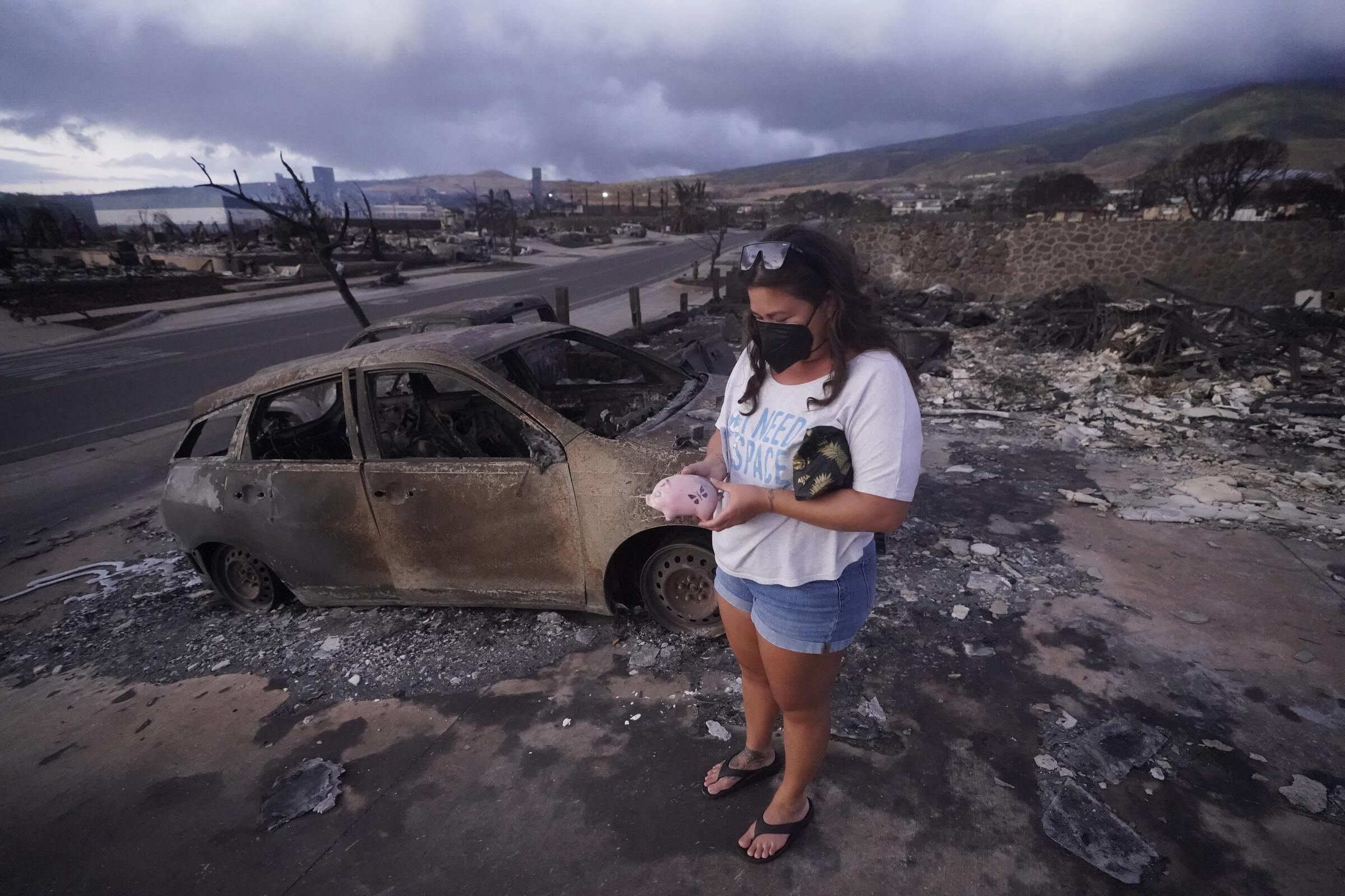 A woman stands in a smoky ruin holding a small pink piggy bank.