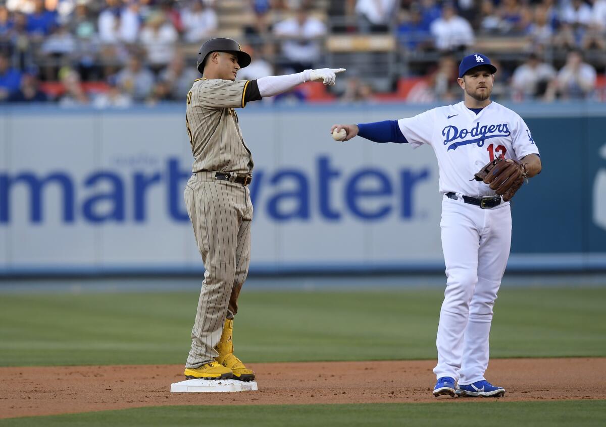 The Padres' Manny Machado celebrates at second base after hitting a double as Max Muncy of the Los Angeles Dodgers reacts 
