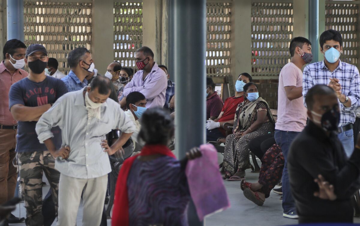 People wait for their results of COVID-19 test at a government hospital in New Delhi