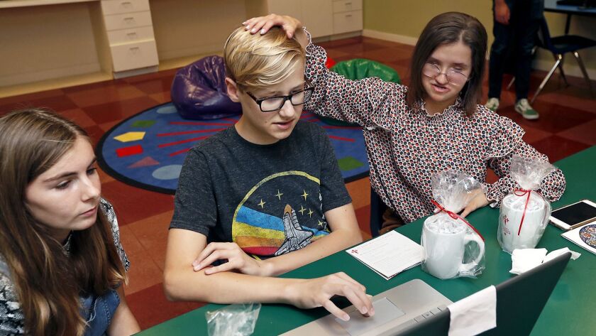 Abby Gordon, 15, Cooper Hubbard, 14, and Lucie Courtois, 18, from left, look at code during a class at St. James Episcopal Church in Newport Beach, where sighted and sight-impaired teenagers were learning how to direct a telescope to capture images of asteroids.