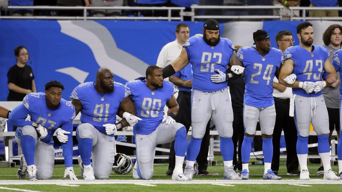 Detroit Lions players link arms and kneel during the national anthem Sunday.