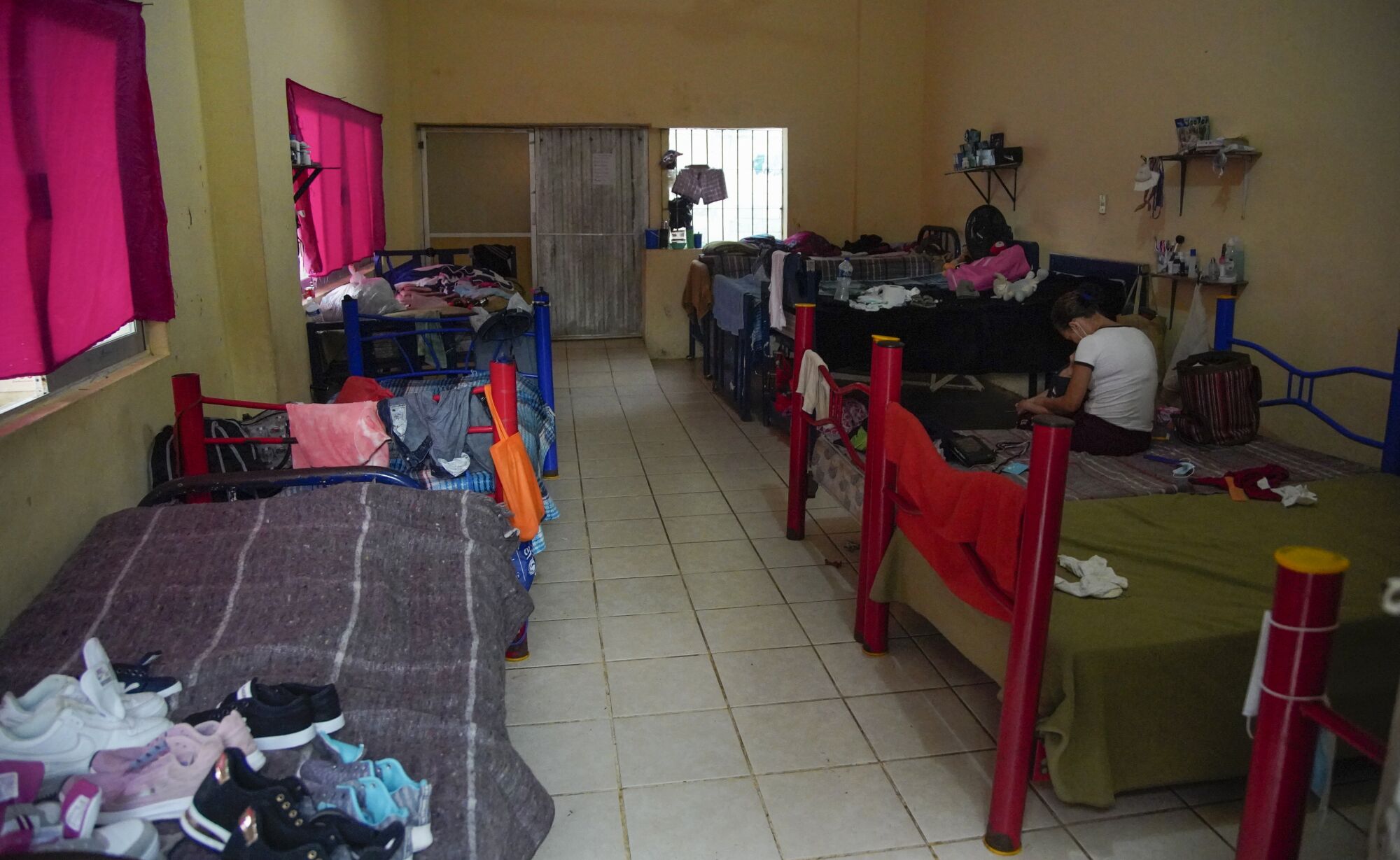 A woman sits on a bed in a room at a migrant shelter in Tapachula