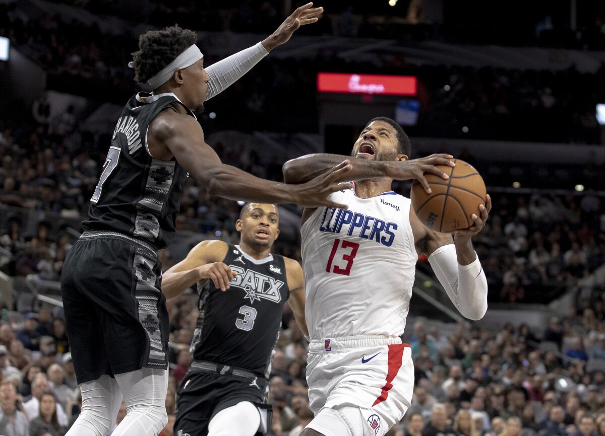 Clippers forward Paul George gathers himself to elevate for a layup as he's defended by the Spurs' Josh Richardson