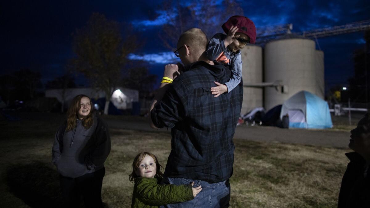 Camp fire evacuees Suzie and Nathan Thomas, with daughter Angel, 5, and sons Wyatt, 3, and Nathan II, 7, wait in line for a free meal at a makeshift campground.