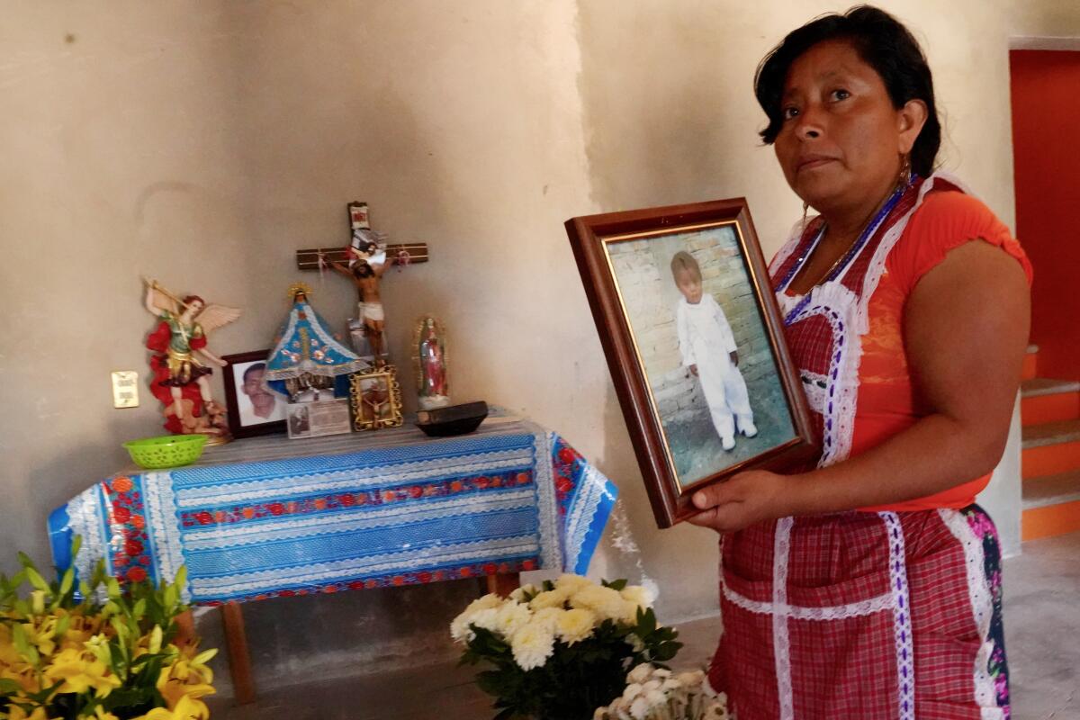 Maria de Jesus Poblado Margarito, 37, mourns the loss of her son, Israel Mendoza Pasado, at home in Alcozacan. She is holding a photo of Israel when he was a a year and a half old.
