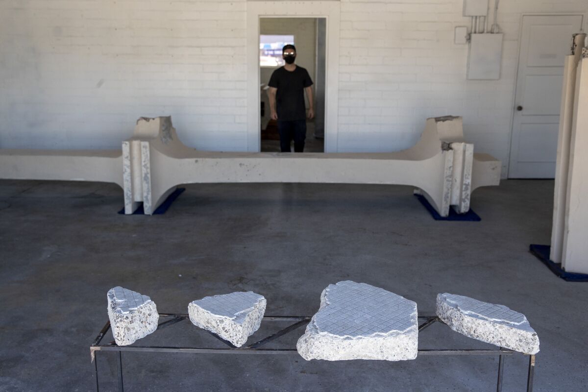 Cayetano Ferrer, dressed in black, is seen standing in a doorway before a section of column from LACMA's facade.