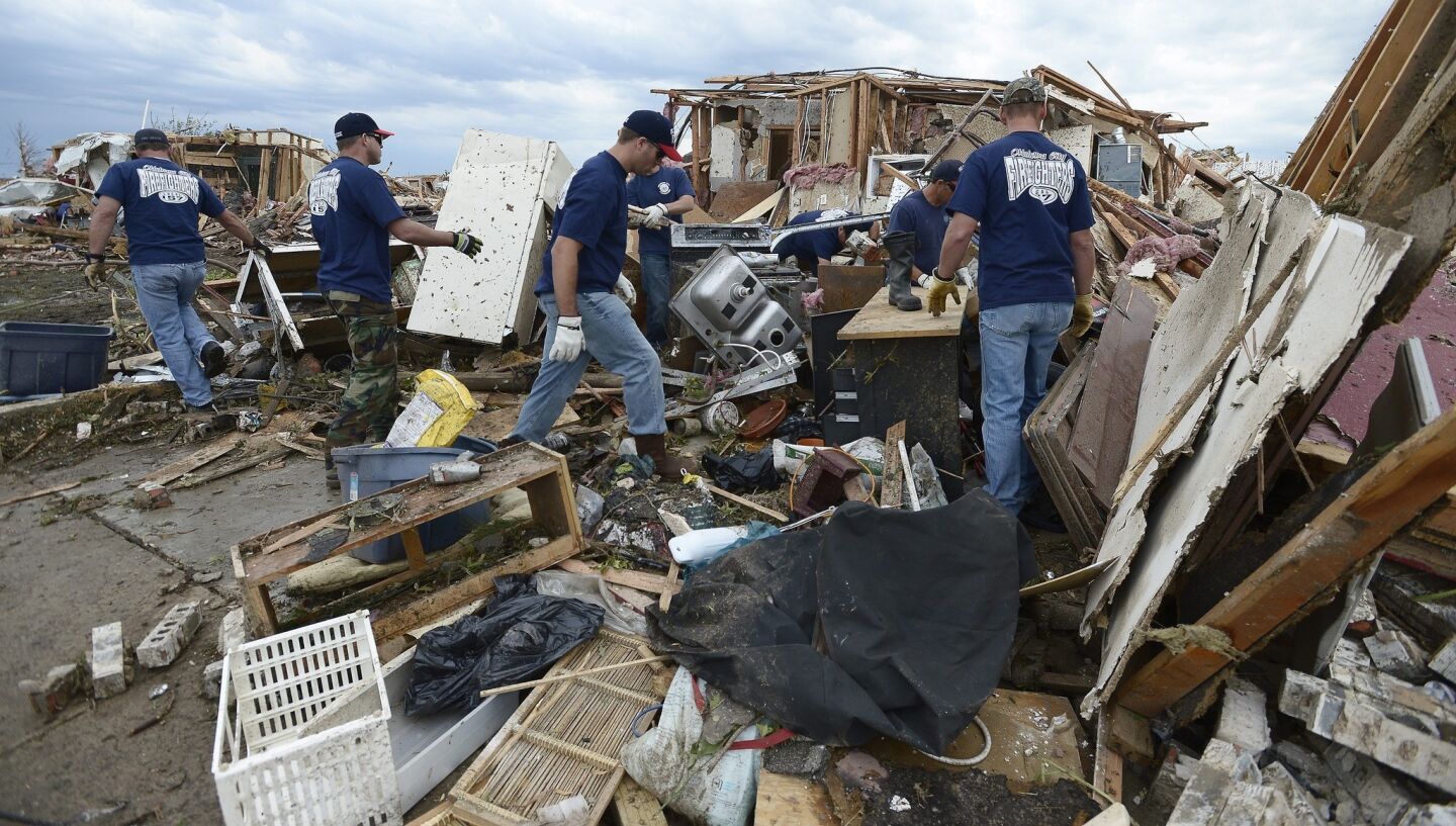 Firefighters help a fellow firefighter recover belongings from the rubble of his home in Moore, Okla.