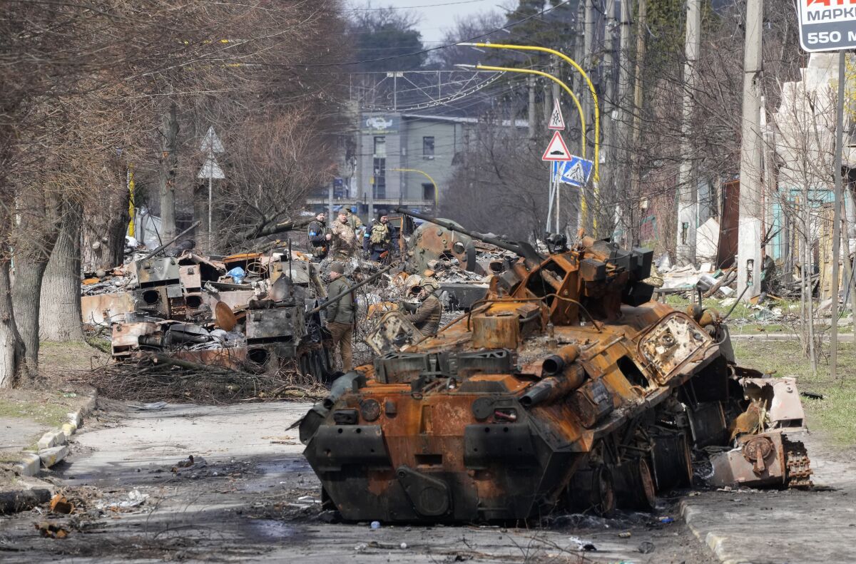 Ukrainian soldiers examine destroyed Russian military vehicles. 