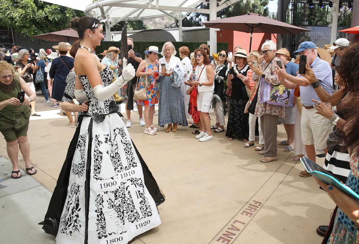 Lucy Landherr, modeling a dress by artist Nancy Swan, poses for pictures at the Festival of Arts runway fashion show.