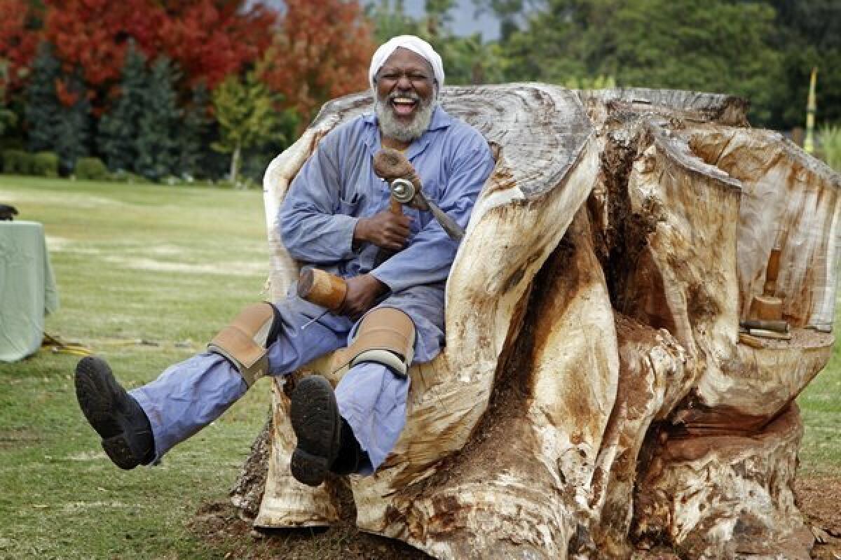 Compton sculptor Charles Dickson takes a break from carving a bench from this earpod, a South American tree with a trunk that was 5 feet in diameter, on the grounds of the Los Angeles County Arboretum and Botanic Garden in Arcadia.