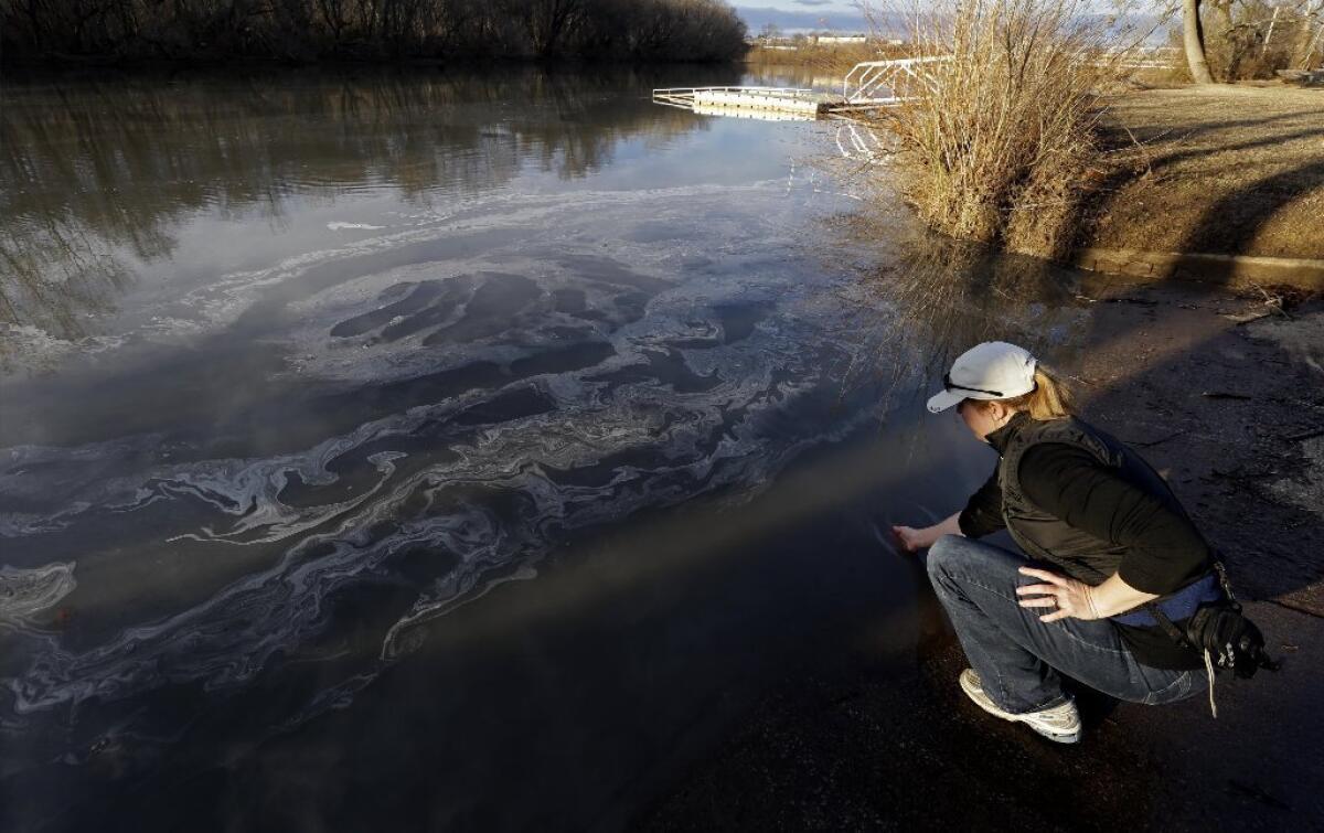 Amy Adams, North Carolina campaign coordinator with Appalachian Voices, dips her hand into the Dan River in Danville, Va., as signs of coal ash appear in the river.